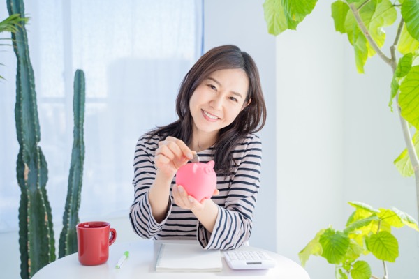 Woman depositing money into piggy bank 